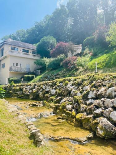 a house on a hill next to a river at Domaine Du Moulin Vallée Heureuse in Poligny