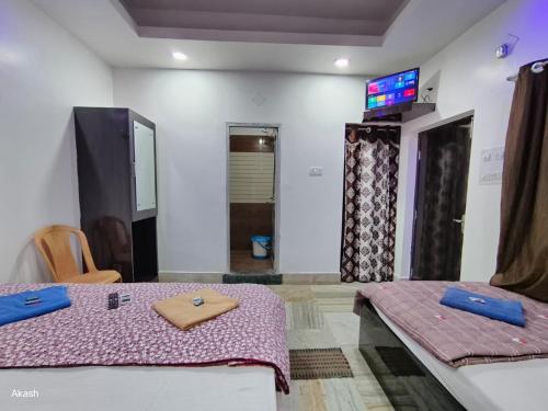 a room with two beds and a tv on the wall at Hotel Bobby house in Puri