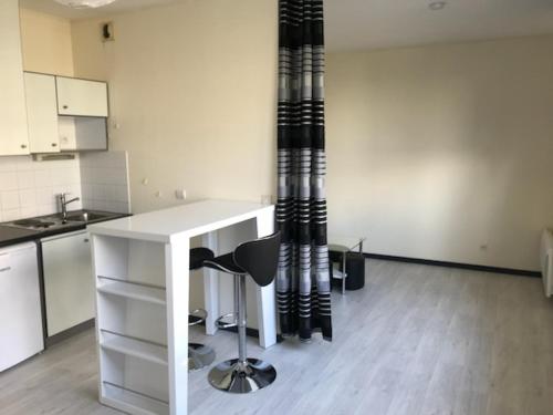 une cuisine avec un comptoir blanc et une chaise noire dans l'établissement GRAND STUDIO MER ET PORT DES MINIMES, à La Rochelle