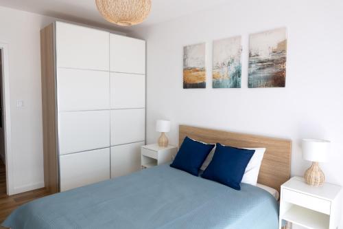ein Schlafzimmer mit einem Bett mit blauen Kissen in der Unterkunft Apartament z Mewami - Dziwnów Bridge Apartaments & Spa in Dziwnów