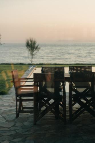 a wooden table and two chairs next to the ocean at Real Life Homes luxurious seafront villas each with their own private pools in Korakokhórion
