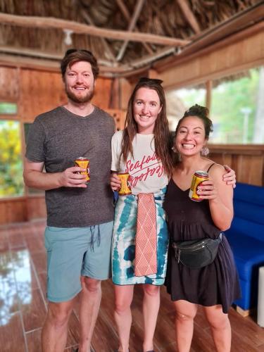 a group of three people standing together holding drinks at El Retiro Lanquin in Lanquín