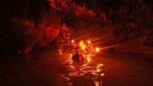 a group of people standing in the water with candles at El Retiro Lanquin in Lanquín