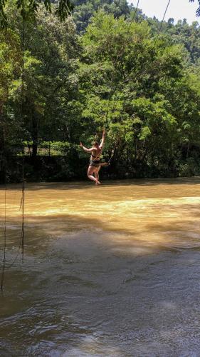 a person on a rope swing over a body of water at El Retiro Lanquin in Lanquín