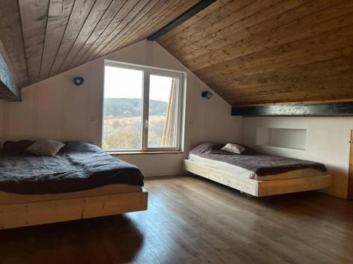 two beds in a room with a large window at Cabana Tudor in Aiud