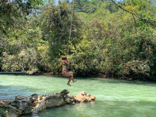 a woman jumping into a river in a rope swing at El Retiro Lanquin in Lanquín