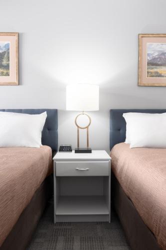 a bedroom with two beds with a nightstand between them at Copper Mountain Inn and Suites in Princeton