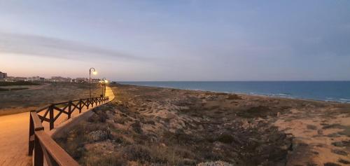 a beach with a fence and the ocean at dusk at Sunny apartments in La Mata, Azul Beach 2 in Torrevieja