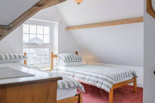 two beds in a room with a window at Westward House - Norfolk Cottage Agency in Sheringham