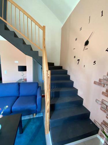 a staircase with a blue couch and a clock on the wall at Well-being in Eifel in Nettersheim