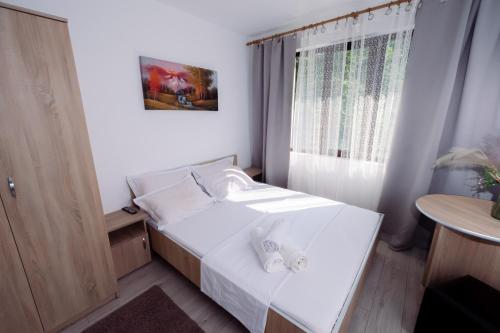 een kleine slaapkamer met een wit bed en een raam bij Complex Stoican in Băile Herculane