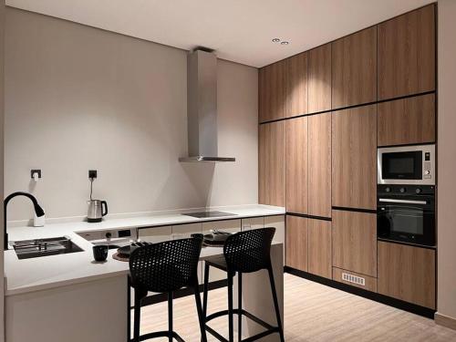 a kitchen with two bar stools and a microwave oven at Luxury apartment with self check-in in Riyadh