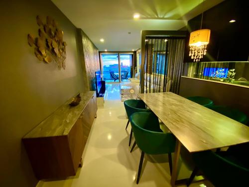 a dining room with a wooden table and green chairs at Lux SL Luxury Style of Life in Pattaya Central