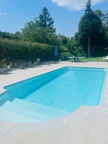 a large blue swimming pool with chairs and trees at Domaine Du Moulin Vallée Heureuse in Poligny