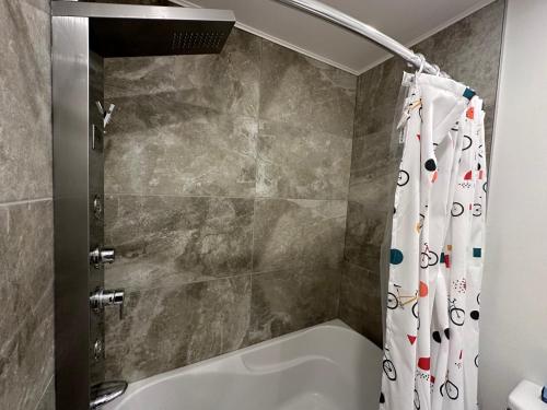 uma casa de banho com uma banheira e uma cortina de chuveiro em Condos Vacances MSA AVEC PISCINE ET SPAS OUVERTS À L'ANNÉE INCLUS em Beaupré