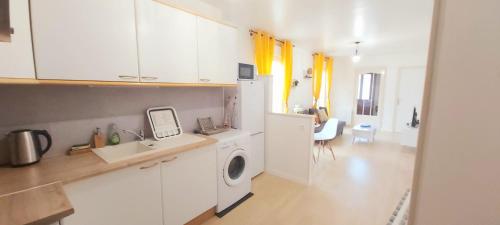 uma cozinha com armários brancos e uma máquina de lavar roupa em Le Petit Martin ~T2 cosy ~ Netflix ~ Parking ~ Animaux bienvenus 