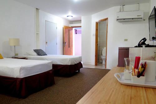 a hotel room with two beds and a table at Hotel Normandie Limited in Port-of-Spain
