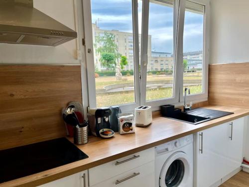 un comptoir de cuisine avec un lave-linge et une fenêtre dans l'établissement AZUR Reims au bord de l'eau - Avec Parking, à Reims