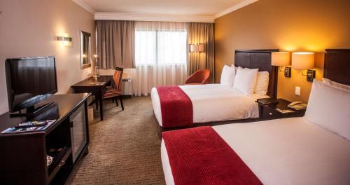 a hotel room with two beds and a flat screen tv at Southern Sun Pretoria in Pretoria