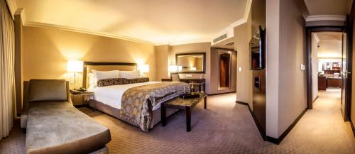 a hotel room with a large bed and a chair at Southern Sun Pretoria in Pretoria