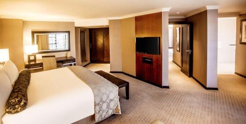 a hotel room with a bed and a flat screen tv at Southern Sun Pretoria in Pretoria