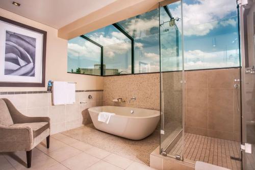 a bathroom with a tub and a glass shower at Southern Sun Pretoria in Pretoria