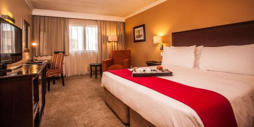 a hotel room with a large bed and a television at Southern Sun Pretoria in Pretoria
