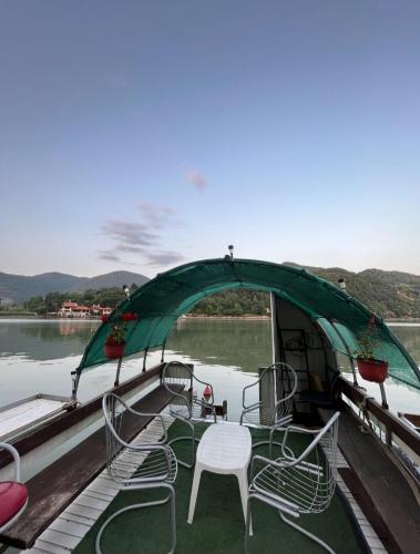 a boat with a green cover and chairs on the water at Vikendica Teodora - Zvornik in Zvornik