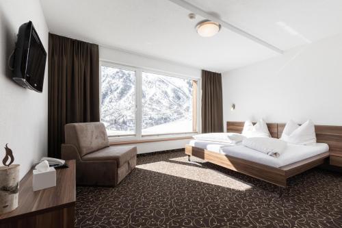 Habitación de hotel con cama y silla en Hotel Garni Birkhahn, en Galtür