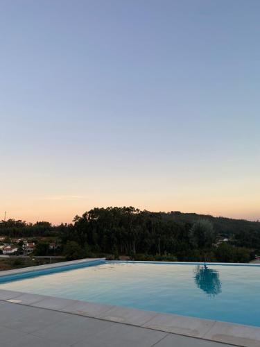 a large swimming pool with a sunset in the background at CASA DAS QUINTÃES in Figueiredo
