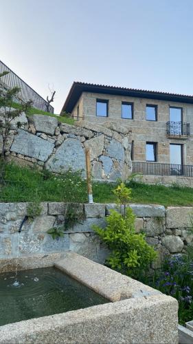 a stone wall with a pond in front of a building at CASA DAS QUINTÃES in Figueiredo