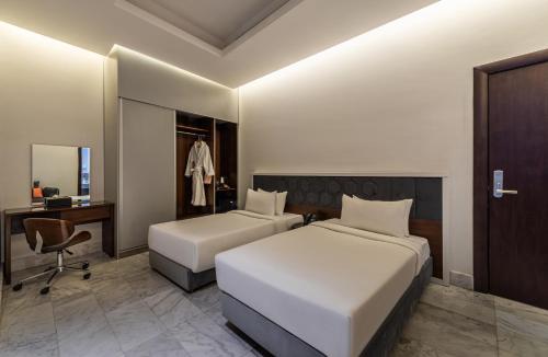 a hotel room with two beds and a desk at HDB Al Sahafa in Riyadh