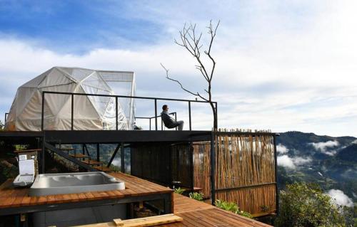 a person sitting on top of a house with a tent at Glamping La Montaña Sagrada in Medellín
