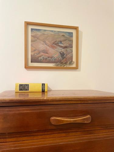 a painting above a dresser with a book on it at פסק זמן in Ramat Shlomo