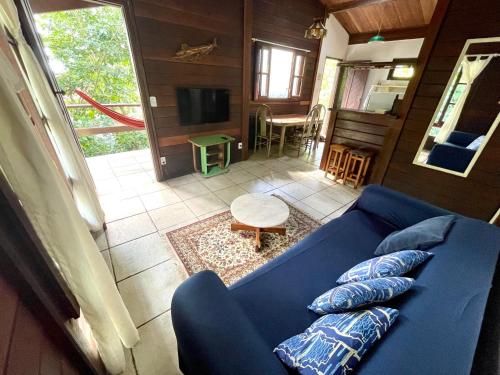 a living room with a blue couch and a television at Casa Selva - Vila do Abraão - Ilha grande in Abraão