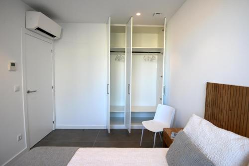 a bedroom with a bed and a chair and a closet at Duerming Sanxenxo Silgar VUT in Sanxenxo