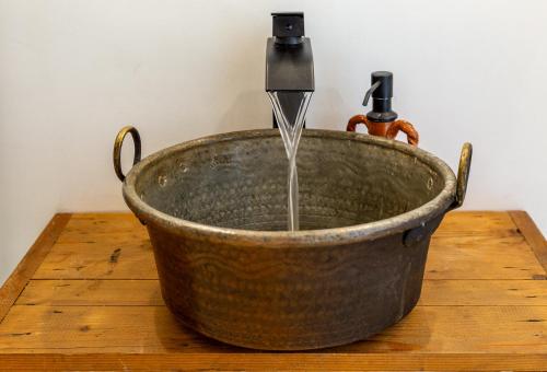 un secchio metallico con una fontana su un tavolo di legno di Crobi Museum and Suites a Cagliari