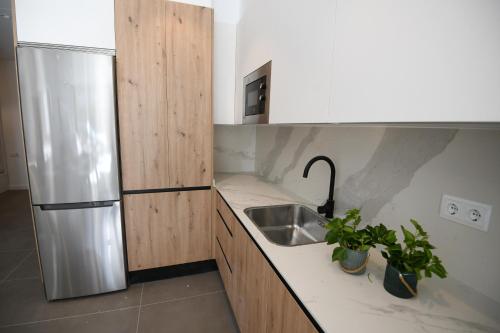 a kitchen with a sink and a stainless steel refrigerator at Duerming Sanxenxo Silgar VUT in Sanxenxo