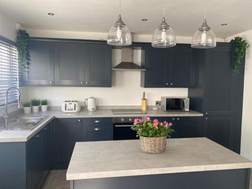 a kitchen with black cabinets and a table with flowers on it at Private room in modern detached house in Killyhevlin