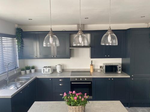 uma cozinha com armários azul marinho e candeeiros de prata pendentes em Private room in modern detached house em Killyhevlin