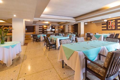 a dining room with tables and chairs with blue and white tablecloths at Hotel Faranda Express Puerta del Sol Porlamar in Porlamar