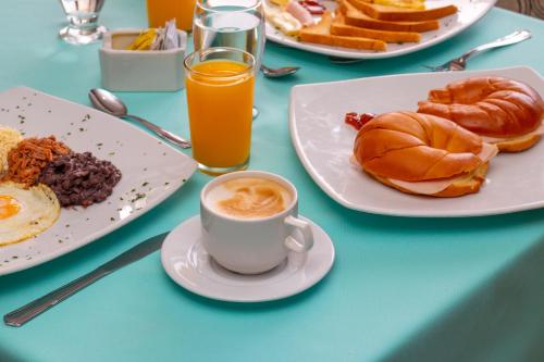 a table with plates of breakfast foods and a cup of coffee at Hotel Faranda Express Puerta del Sol Porlamar in Porlamar