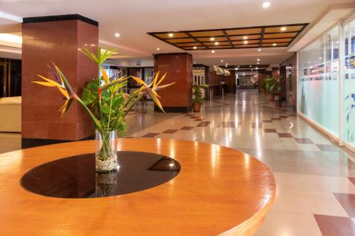 a vase of flowers sitting on a table in a lobby at Hotel Faranda Express Puerta del Sol Porlamar in Porlamar
