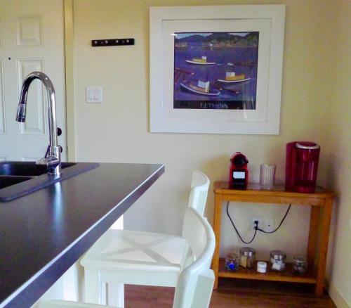 cocina con fregadero y encimera con 2 sillas blancas en AnnArthur Guest House, en Nanaimo