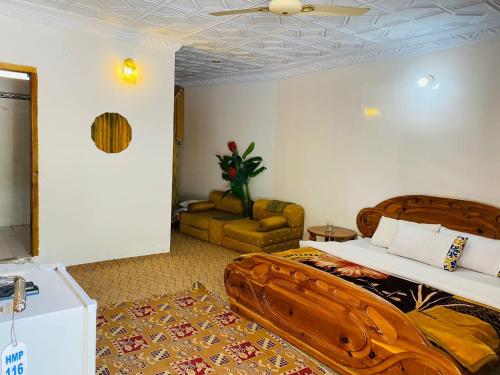 een slaapkamer met een houten bed en een bank bij Hotel Miandam Palace in Mingora