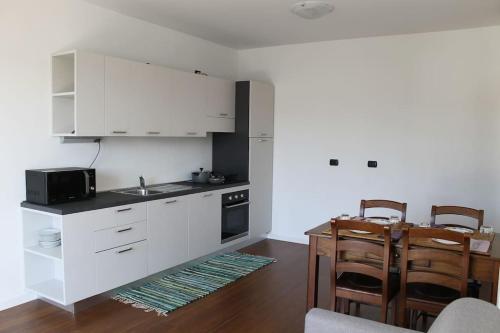 a kitchen with white cabinets and a table and chairs at Snorky apartments in Azzano San Paolo
