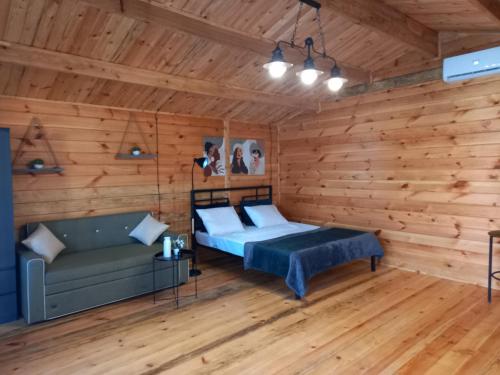 a bedroom with wooden walls and a bed and a couch at Гостевой дом Фазенда in Pizunda