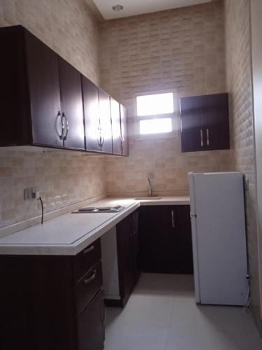 a kitchen with black cabinets and a white refrigerator at Quiet Rooms 7 Serviced Apartments in Riyadh