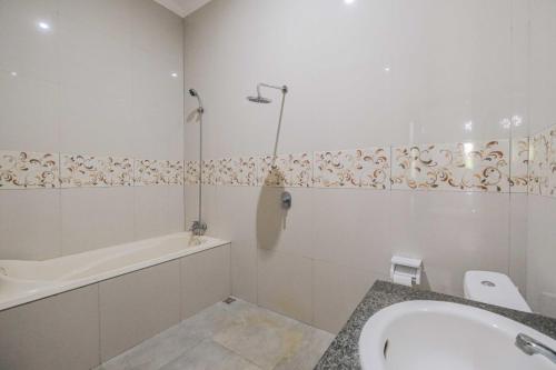 uma casa de banho branca com uma banheira e um lavatório e uma banheira em The Fortune Guest House em Tejakula