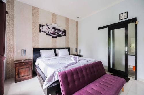 um quarto com uma cama grande e um sofá roxo em The Fortune Guest House em Tejakula